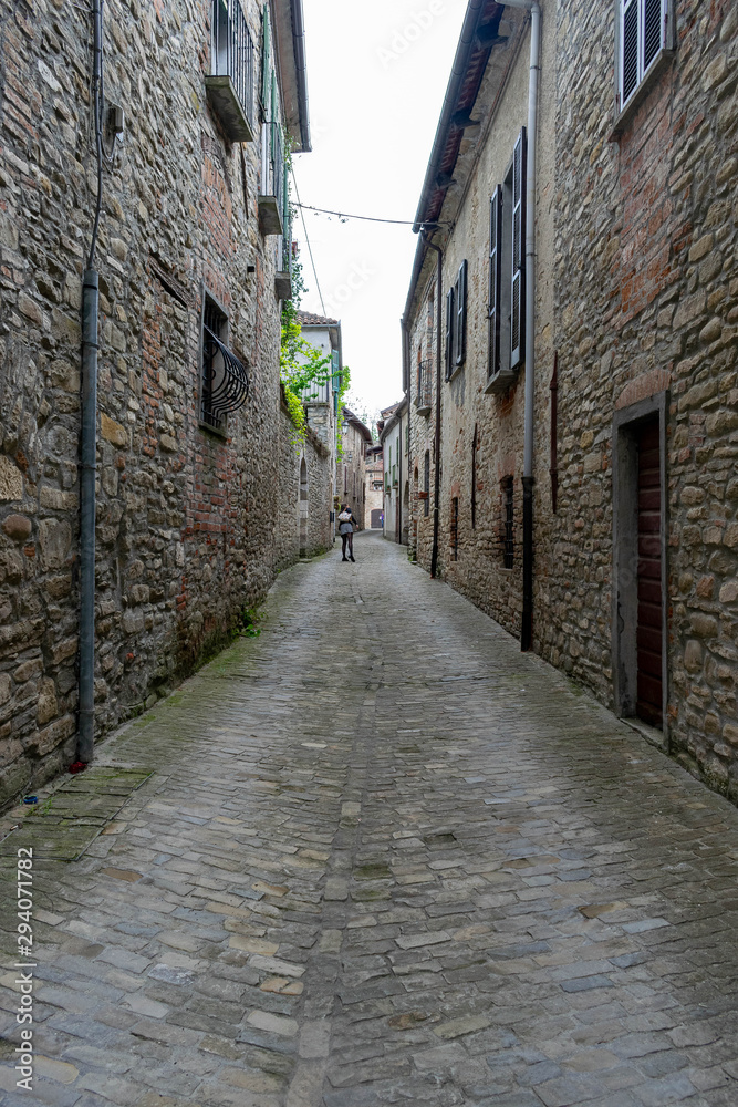 A solitary man walks among the narrow streets of a small medieval town