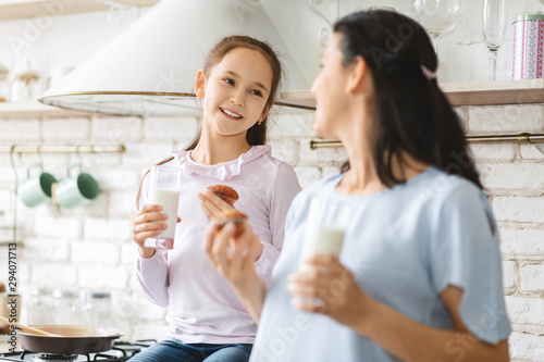 Happy mother and daughter having a bite in kitchen together