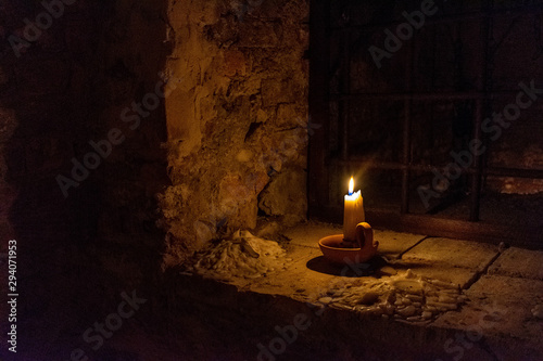 Candlestick resting on the sill of an old window with iron gratings