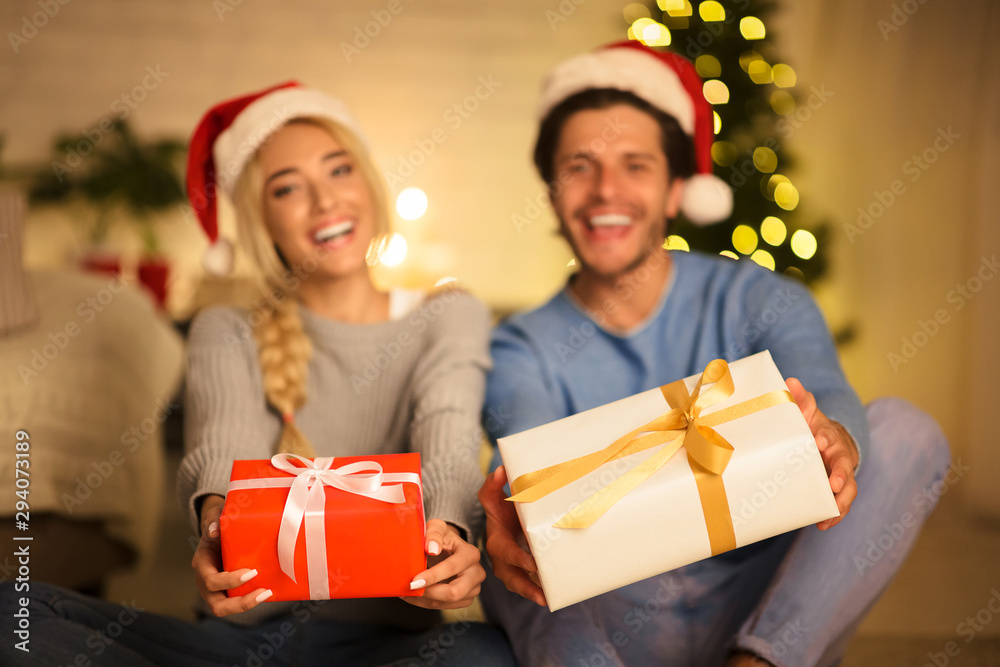 Merry Christmas. Couple holding gift boxes, stretching to camera Merry Christmas. Couple holding gift boxes, stretching to camera