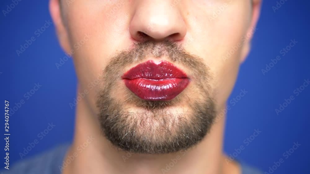 close-up. A bearded man with painted lips licks them sexually. close-up. A bearded man with painted lips licks them sexually.