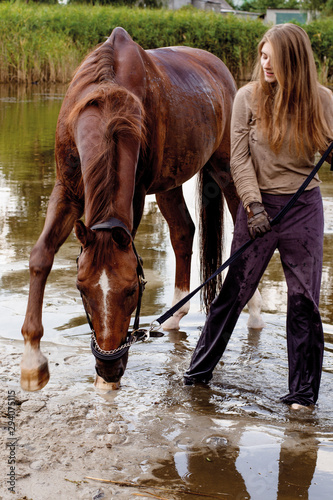 photo young rider in gloves walks with a horse in a pond