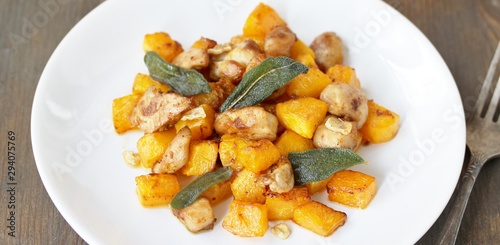 dish with pumpkin. fried chicken fillet and pumpkin cubes with sage (chips from sage). a dish on the table on a sunny day. autumn dish with pumpkin.