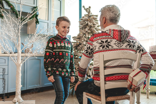 Фотография grandfather with a white beard sitting hides the Christmas present