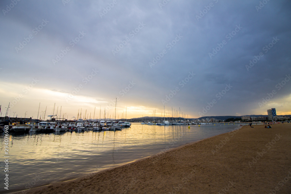 Dramatic Sunset Sky over the Beach of Palamós on the Spanish Costa Brava with Yachts in the Foreground
