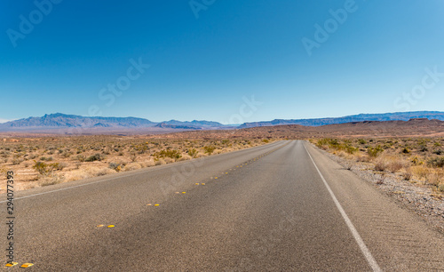 View of Highway with No Cars for Miles With Mountains in the Background