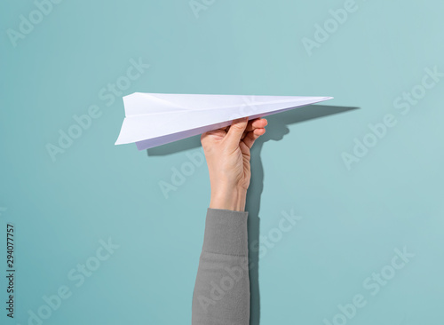 Person holding a paper airplane with hard shadow