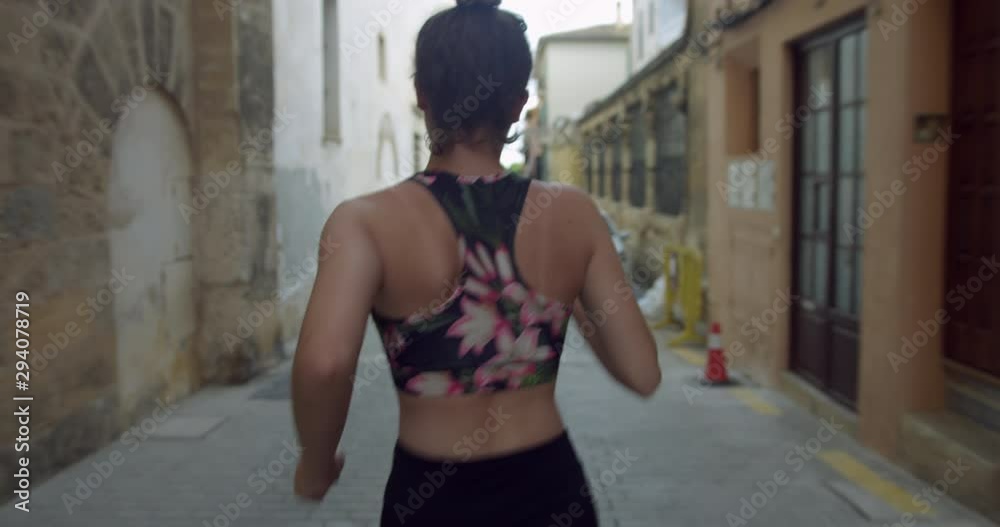 Young Blonde Woman Jogging on City Street. Active Girl Running in Fitness Gym Top in Spanish Town. Health and Wellness Female Runner Exercising Outdoors. Young Blonde Woman Jogging on City Street. Active Girl Running in Fitness Gym Top in Spanish Town. Health and Wellness Female Runner Exercising Outdoors.