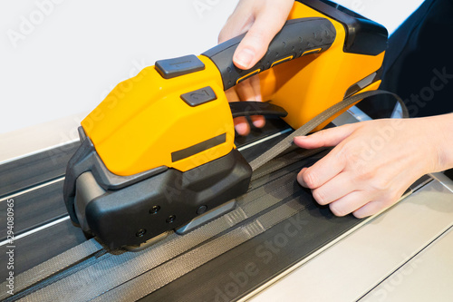 Industrial packer. Packing cargo with strapping tape. Adhesive plastic packing tape. Packaging of expensive goods. Portable equipment for packing boxes and boxes. Equipment for packing goods.
