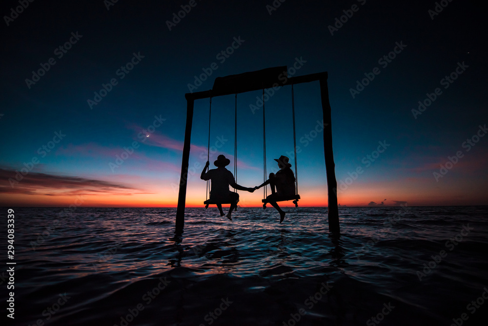 Couple contemplating an amazing sunset at Holbox Island in the Caribbean Ocean of Mexico - obrazy, fototapety, plakaty 