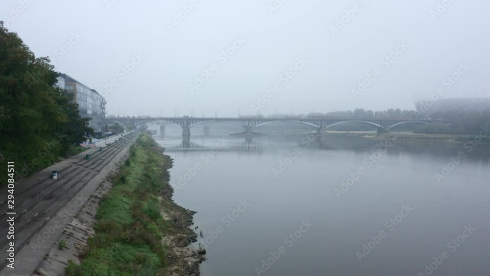 Drone flies to a bridge in the fog in the city of Warsaw. Poland. Aerial view of the river and bridge on a foggy day. Drone flight on a bridge with cars and public transport in the fog. 4K Drone Shot. Drone flies to a bridge in the fog in the city of Warsaw. Poland. Aerial view of the river and bridge on a foggy day. Drone flight on a bridge with cars and public transport in the fog. 4K Drone Shot.