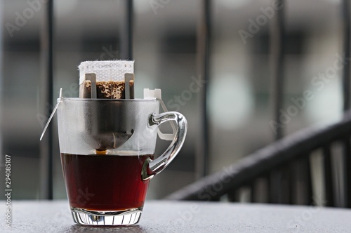 Drip or brewed coffee on wooden table at balcony, paper dripping bag on a cup