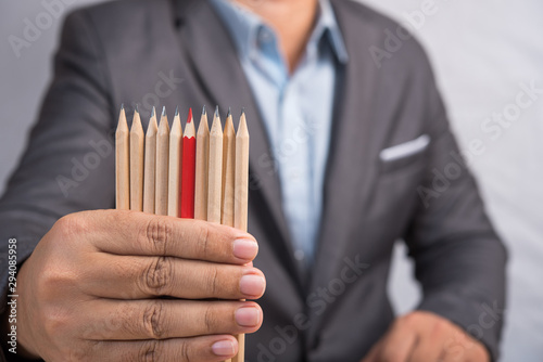 businessman in suit select a red color pencil from a different group of brown