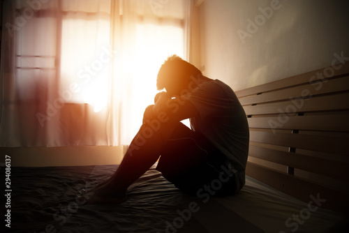 Foto desperate man in silhouette sitting on the bed with hands on head