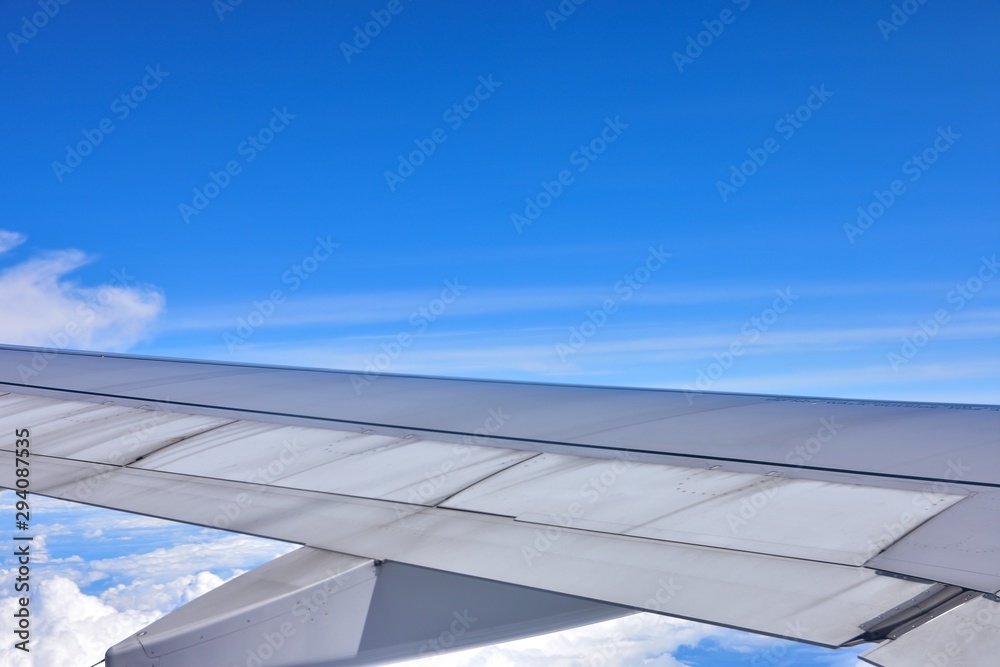 Fototapeta premium Close-up the airplane wing flying in the sky. Blue sky and cloudy background.
