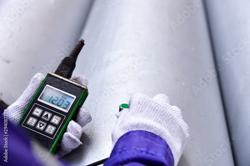 Inspector measuring thickness the pipe with UTM (Ultrasonic thickness measurement).  Selective focus on the display. photo