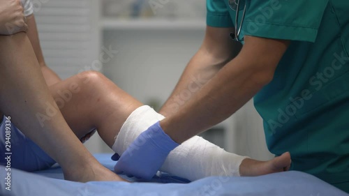 Professional surgeon applying gypsum on female patient leg, trauma, healthcare