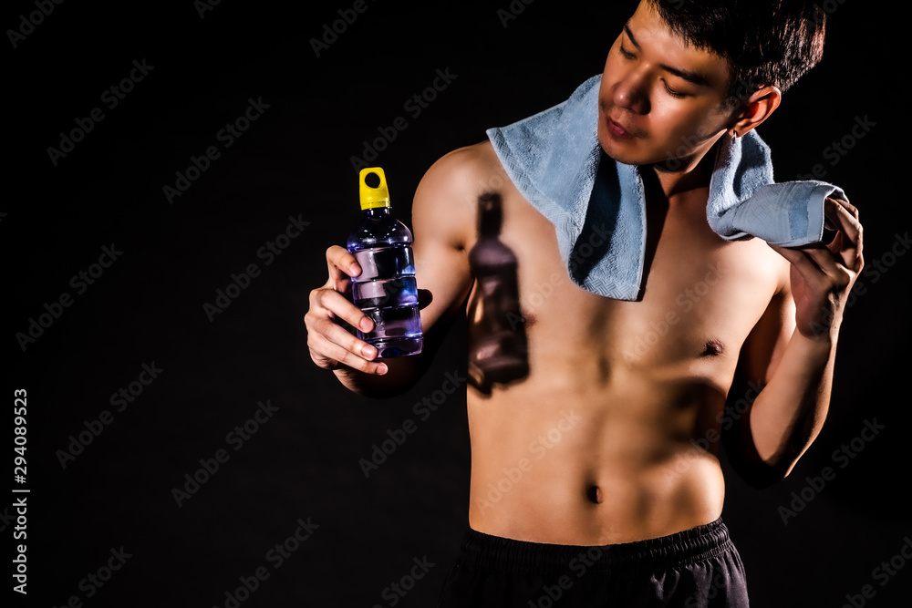 sport man standing holding a towel and bottled water and showing muscle bodybuilding on black backgrounds, fitness concept, sport concept sport man standing holding a towel and bottled water and showing muscle bodybuilding on black backgrounds, fitness concept, sport concept