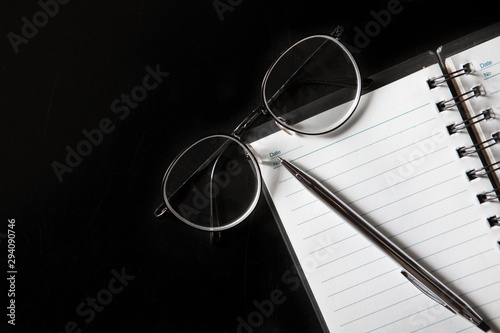 Top view of Pen, notebook, glasses,on black background and copy space