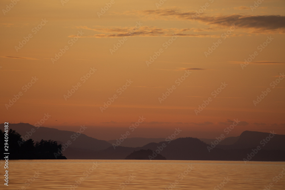 Landscape sunset pink hues over the mountains, islands, and water of the Pacific Northwest