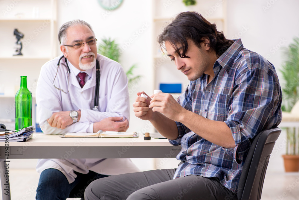 Obraz premium Young male alcoholic visiting old doctor
