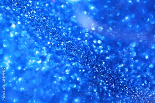 blue glitter background.Christmas festive winter background.Shiny texture with highlights. Blue shining bokeh surface. sparkling shiny paper.Christmas holiday seasonal wallpaper
