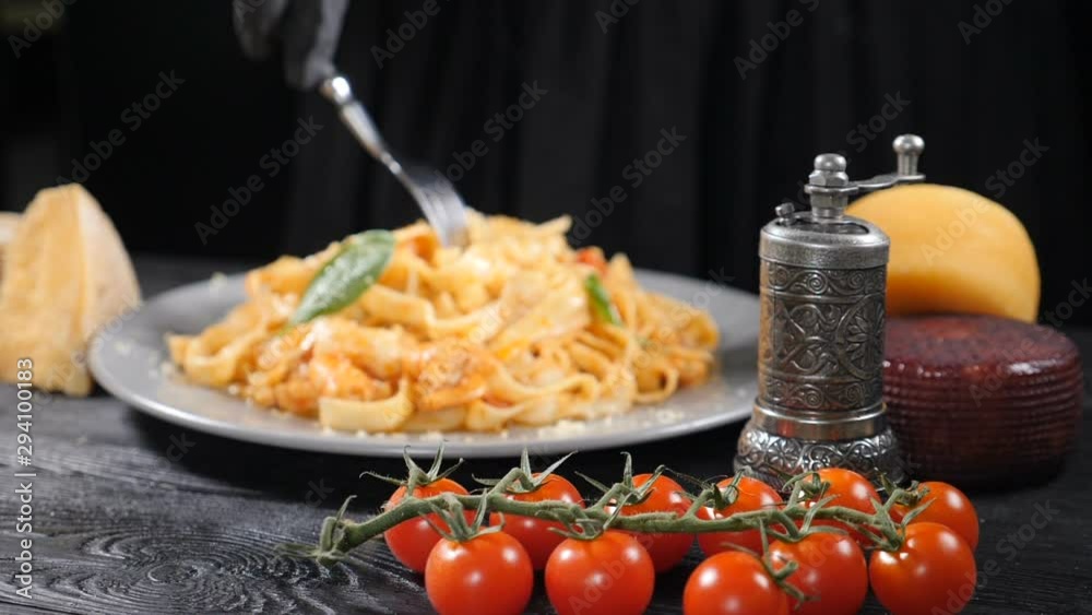Eating seafood pasta with shrimps grated with hard cheese by rolling spaghetti with fork. Italian cuisine concept. Twisting fork with spaghetti. Tasting delicious spaghetti carbonara. Sloiw mo. hd