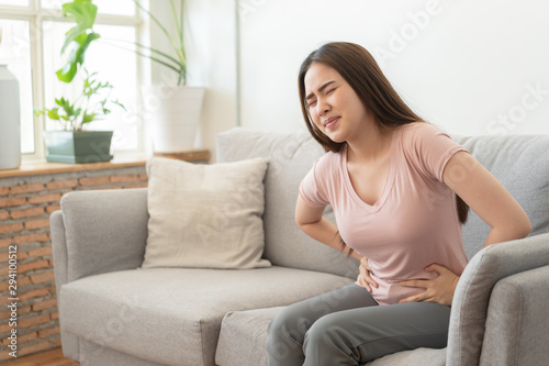asian woman with menstruation and pain period cramps. young women having painful sitting on sofa at her home © sorrapongs