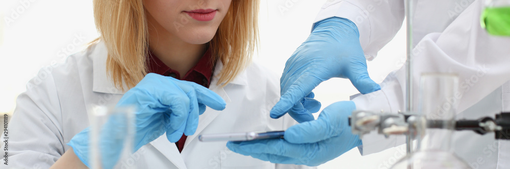 A female doctor in a chemical laboratory holds a smartphone in his hand with display, you can insert a picture or an image you want to write for an advertising company A female doctor in a chemical laboratory holds a smartphone in his hand with display, you can insert a picture or an image you want to write for an advertising company