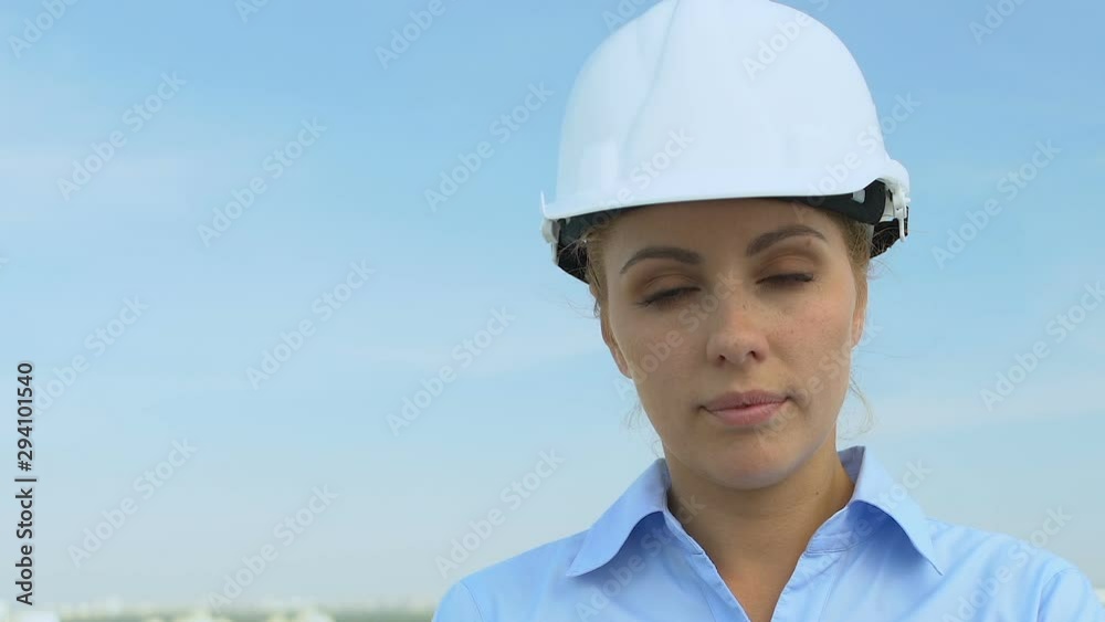 Serious female engineer in helmet looking into camera, profession and experience Serious female engineer in helmet looking into camera, profession and experience
