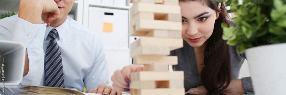 Businessman and businesswoman plays in strategy hand rearranging wooden blocks involved during break at work in office sitting table gaming pile fun joy pastime concept. Businessman and businesswoman plays in strategy hand rearranging wooden blocks involved during break at work in office sitting table gaming pile fun joy pastime concept.