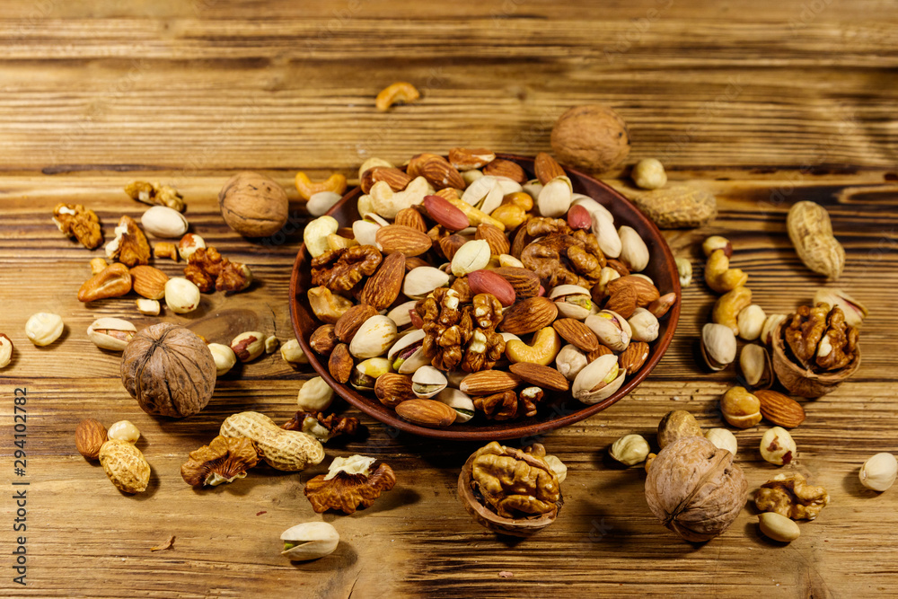 Mixed nuts on wooden table. Walnuts, pistachio, almond, peanut, cashew, hazelnut in ceramic bowl. Healthy eating concept Mixed nuts on wooden table. Walnuts, pistachio, almond, peanut, cashew, hazelnut in ceramic bowl. Healthy eating concept