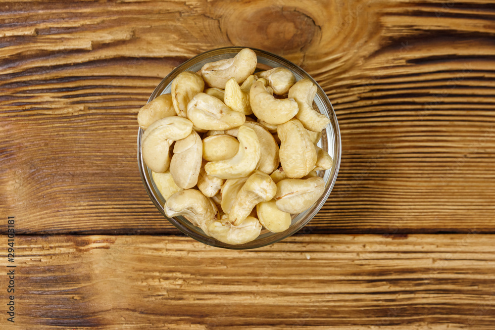 Glass bowl with raw cashew nuts on a wooden table. Top view Glass bowl with raw cashew nuts on a wooden table. Top view