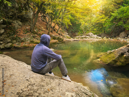 Vászonkép Man in autumn forest and river.
