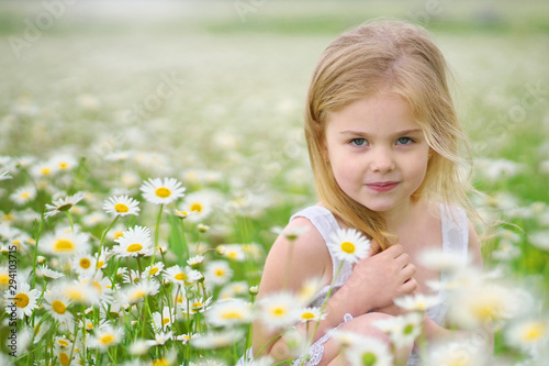 Cute little girl in big camomile meadow.