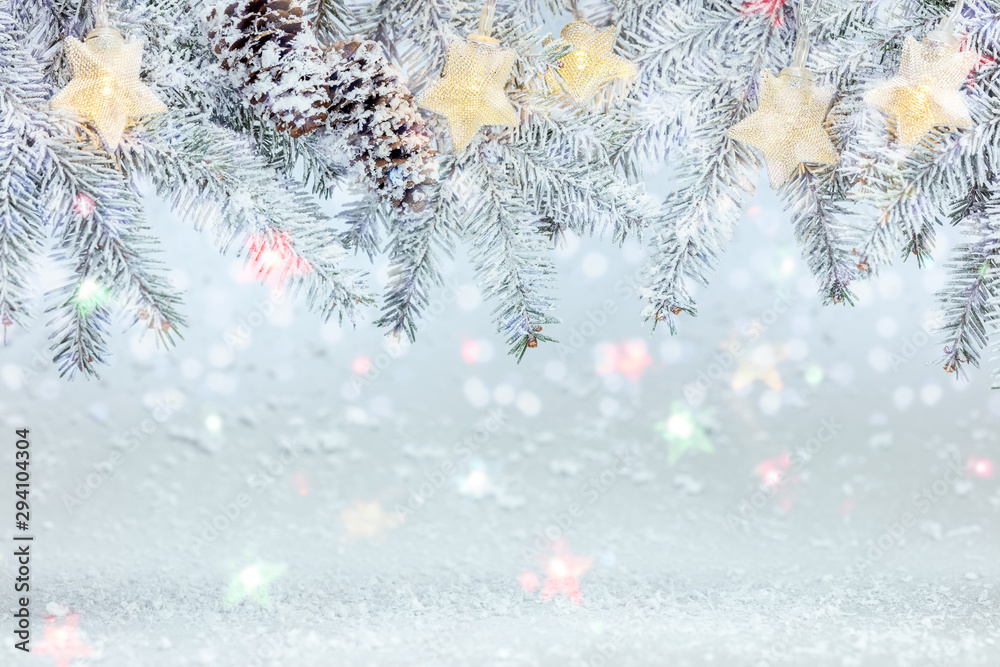 christmas tree branch under snow decorated with glowing star lights garland. frosty winter background