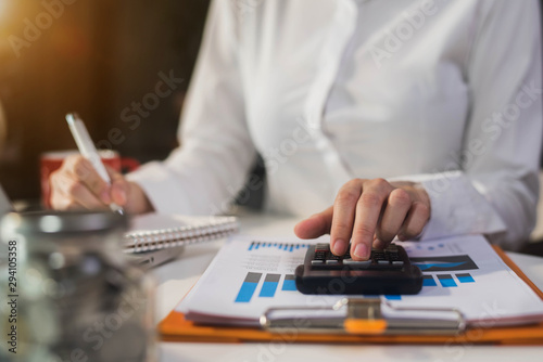 Close up of businessman working on calculator to calculate financial data report, accountancy document and laptop computer at office, business concept.