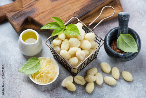 Raw potato gnocchi and some cooking ingredients over beige stone background, studio shot