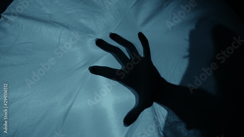Photos Creepy night scene: A woman's silhouette behind the fabric, a hand suddenly hits