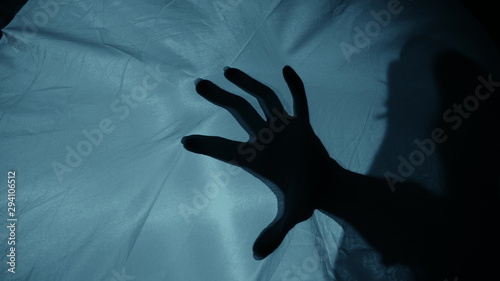 Creepy night scene: A woman's silhouette behind the fabric, a hand suddenly hits the fabric, causing terror and fear