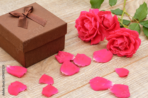 Gift box with rose flowers on the wooden background.