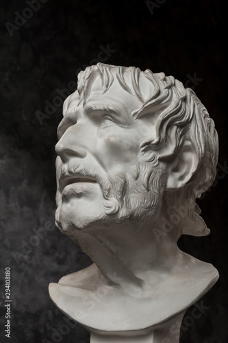 Gypsum copy of ancient statue Seneca head on dark textured background. Plaster sculpture man face.