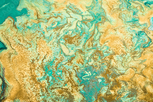 Golden grains are randomly scattered on Free flowing paint. Background or texture in green and yellow colors