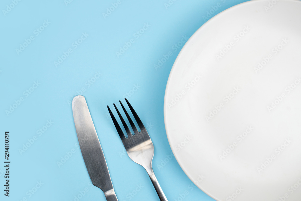 Top view of the plate and spoon on the blue background with the copy space. Top view of the plate and spoon on the blue background with the copy space.