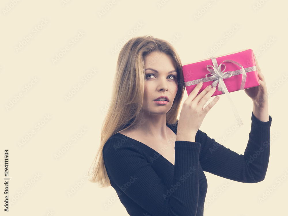 Girl holding present shaking pink gift box Girl holding present shaking pink gift box