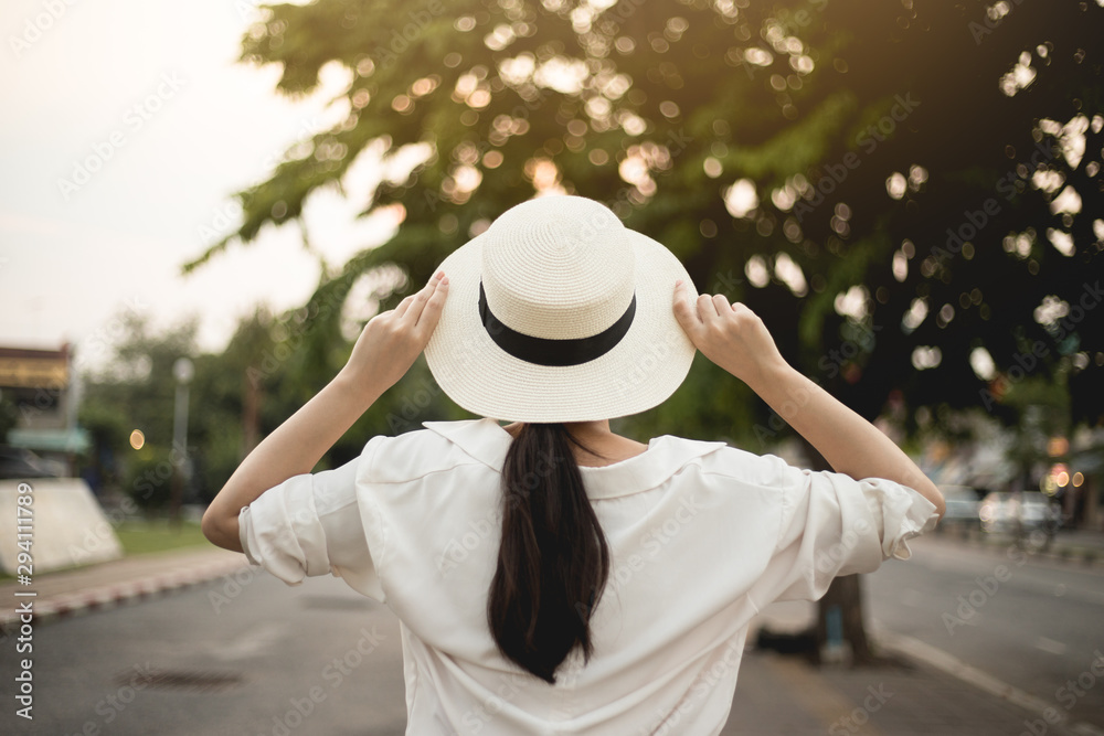 Asian women travel for a summer vacation in Thailand. She has a hat and grabs her hat. In the refreshing concept