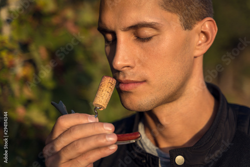 Obraz na plátně young man smelling red wine cork. tasting wine