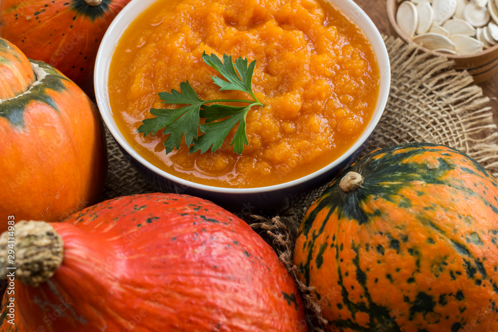 Pumpkin porridge in a bowl among orange pumpkins. Close-up Pumpkin porridge in a bowl among orange pumpkins. Close-up