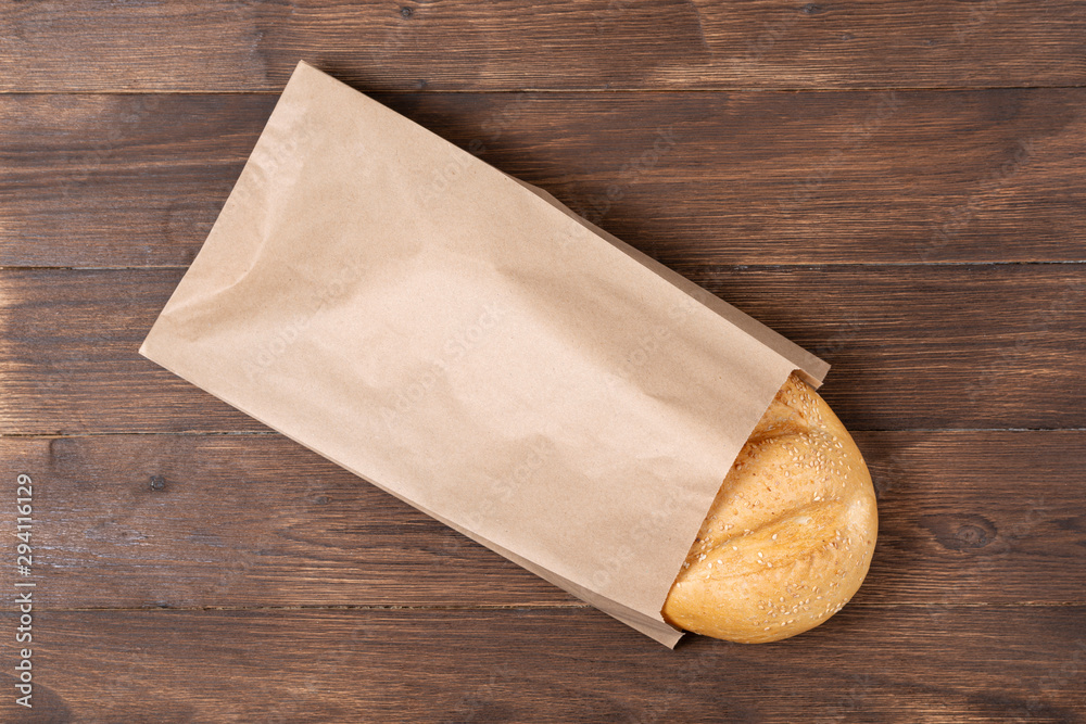 classic loaf in a steam package that is made of recycled material on a wooden background, paper bag concept