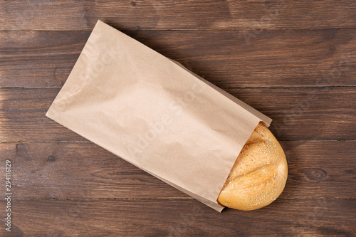 Obraz na płótnie classic loaf in a steam package that is made of recycled material on a wooden background, paper bag concept w salonie